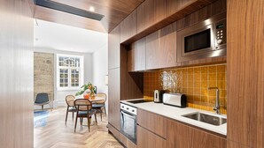 A modern kitchen with wooden cabinets, a microwave, a toaster, and a sink. - GuestReady - Santa Barbara Garden House 12 (Braga)