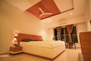 Ein modernes Hotelzimmer mit Bett, Nachttisch, Lampe und Deckenventilator.