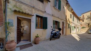 A narrow cobblestone street with a building featuring a door, windows with shutters, and a parked scooter. - VISTA SU MONTECRISTO - VISTA SU MONTECRISTO (Capoliveri)