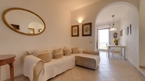 A living room with a sofa, a round mirror, framed pictures, and a dining area with a table and chairs. - VISTA SU MONTECRISTO - VISTA SU MONTECRISTO (Capoliveri)