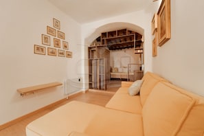 A modern living room with a sofa, a glass cabinet, and a wooden shelving unit.