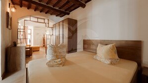 Ein Schlafzimmer mit Holzbalkendecke, einem Bett mit zwei Kissen, einem Schreibtisch und einem Stuhl.