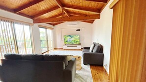 Una sala de estar con techo de madera, un televisor grande y dos sofás.