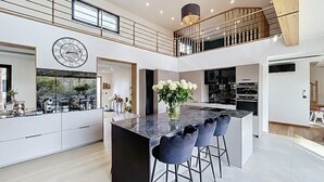 A modern kitchen with a central island, bar stools, and a decorative vase. - Luxury Villa in Grimaud (GRIMAUD)