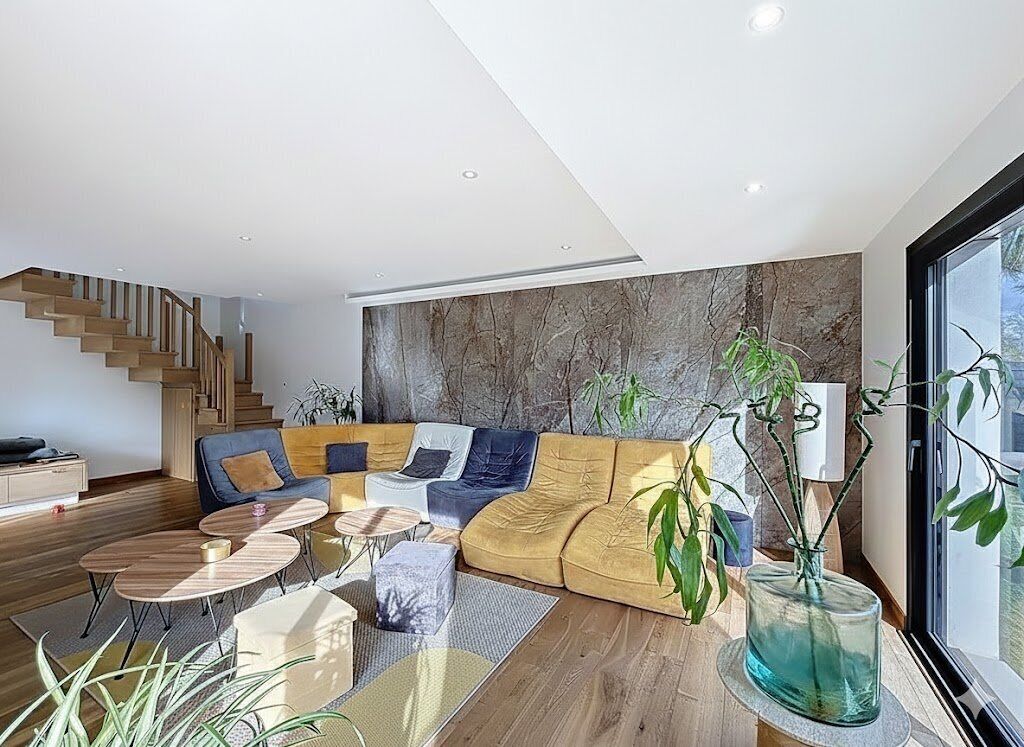 Un salon moderne avec un canapé d’angle, une table basse et un escalier.