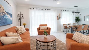 Ein Wohnzimmer mit Sofa, Sesseln, Couchtisch, Esstisch und Stühlen.