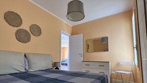 Quarto com cama, cômoda, cadeira e espelho.