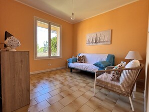 A living room with a sofa, a chair, a lamp, and a painting on the wall. - Capo d'Arco - Agrumeto (Rio Marina)