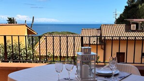 Mesa posta para dois com vista para o mar, um candeeiro e um terraço com guarda.