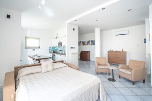 A hotel room with a bed, a dining table, a kitchen area, and a seating area with chairs. - Atelier sul Mare exclusive property near the sea in Minori, Amalfi Coast (Minori)