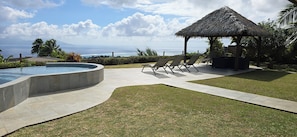 A swimming pool, lounge chairs, a thatched-roof gazebo, and a view of the ocean. - Villa with Pool & Jacuzzi, 180° panoramic view of the sea and Moorea (Punaauia)