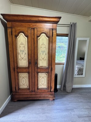 A large wooden wardrobe with decorative panels and a window with curtains. - Rainforest Studio in Volcano- 3miles from National Park (Volcano)