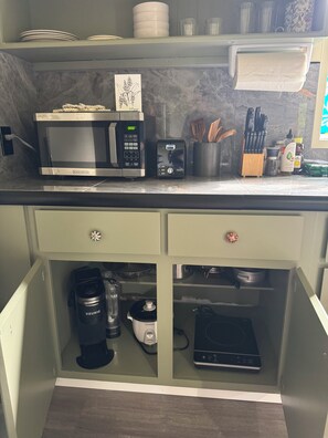 Eine Küche mit Mikrowelle, Kaffeemaschine und Backofen.