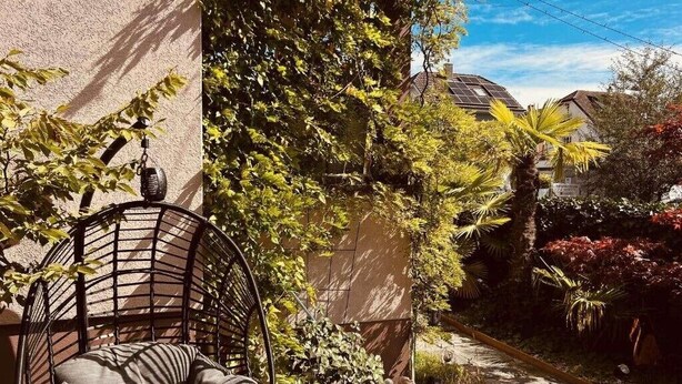 A garden with a chair, a pathway, and a building with a sloped roof. - Centurio 5 :Double room with balcony (Augst)