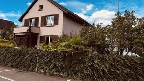 A two-story house with a balcony, surrounded by a hedge and trees. - Centurio 5 :Double room with balcony (Augst)