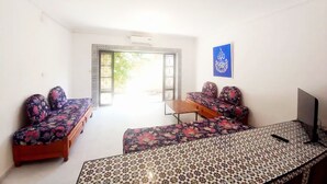Una habitación con un conjunto de sofás, una mesa estampada y un televisor montado en la pared.