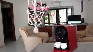 Una sala de estar con sofá, máquina de café y televisor.