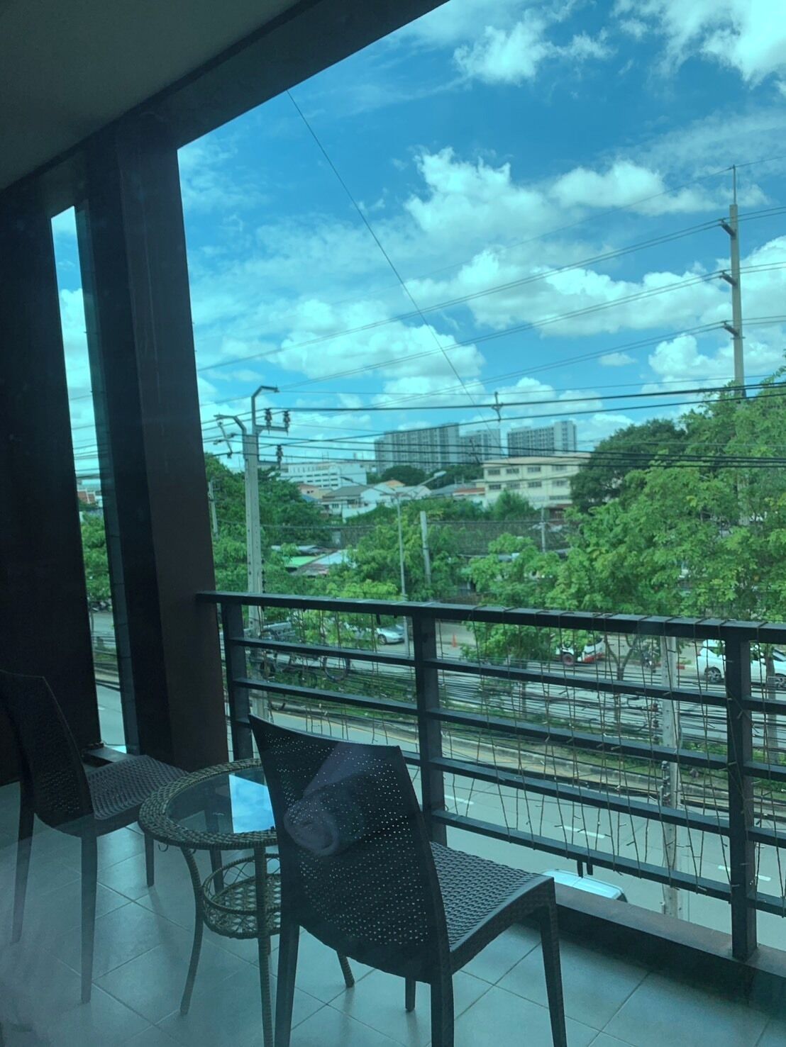 A balcony with a view of a cityscape, including buildings and greenery.