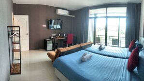 A hotel room with two beds, a desk, a chair, a TV, and a window with curtains.
