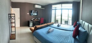 A hotel room with two beds, a desk, a chair, a TV, and a window with curtains.