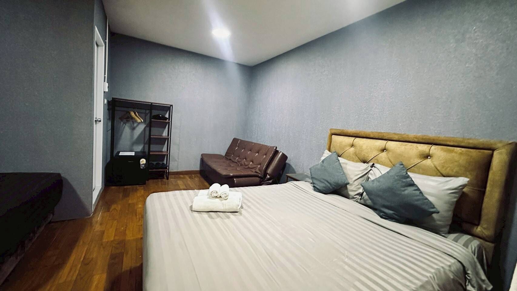 A bedroom with a bed, a chair, a wardrobe, and a bench.