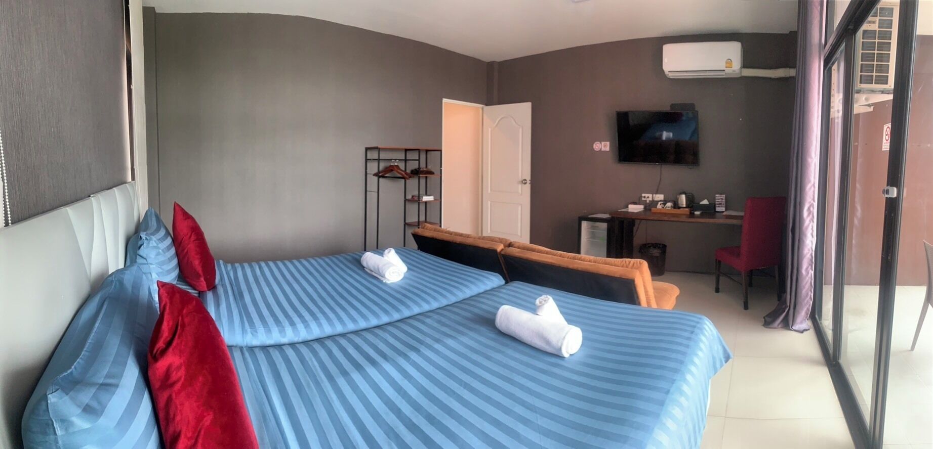 Habitación de hotel con dos camas, un escritorio, un televisor y una silla.