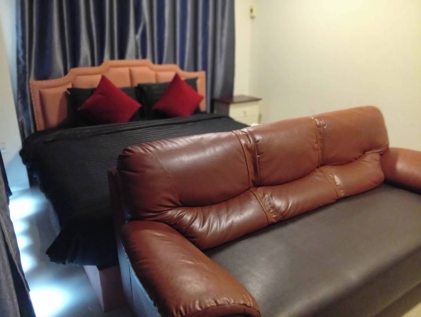 Ein Zimmer mit einem Bett, einem braunen Ledersofa und einem Nachttisch.