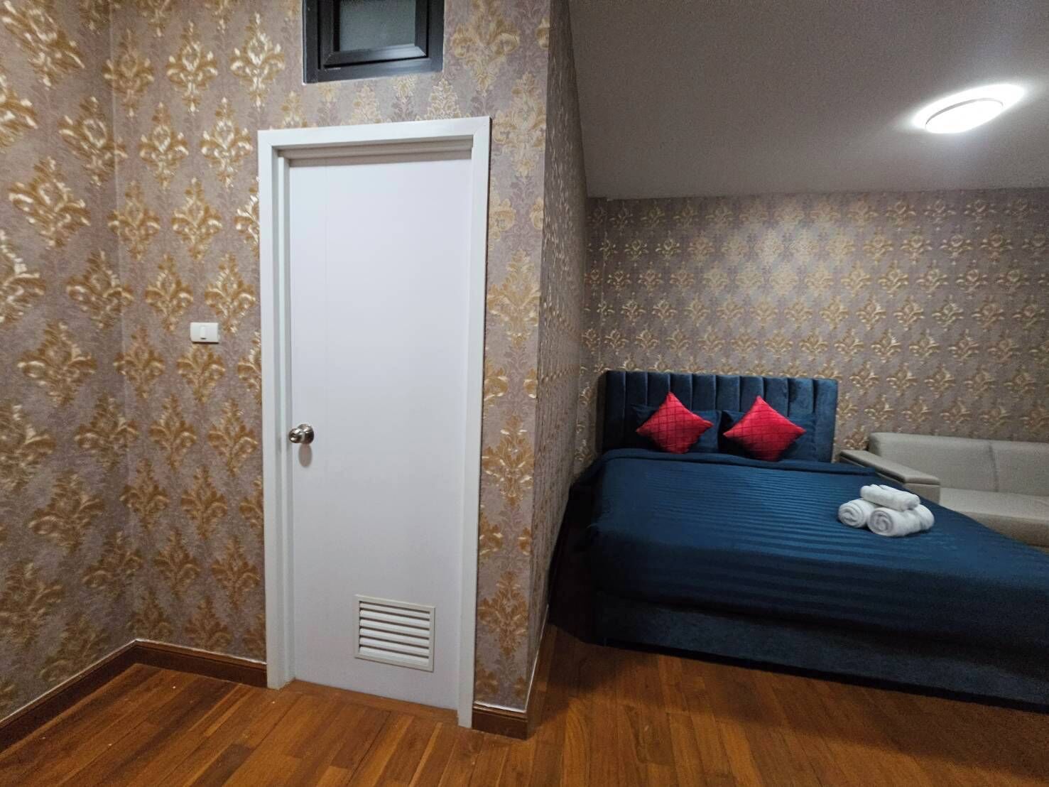 Une chambre à coucher avec un lit, une porte blanche, un papier peint à motifs et un luminaire au plafond.