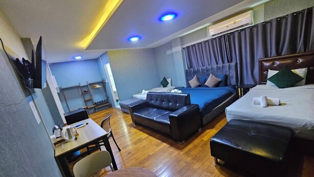 A hotel room with a bed, a sofa, a desk, and a TV.