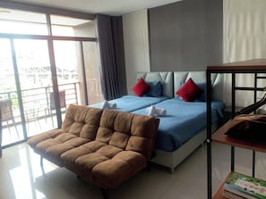 A hotel room with a bed, a brown chair, a small table, and a view of the outside.