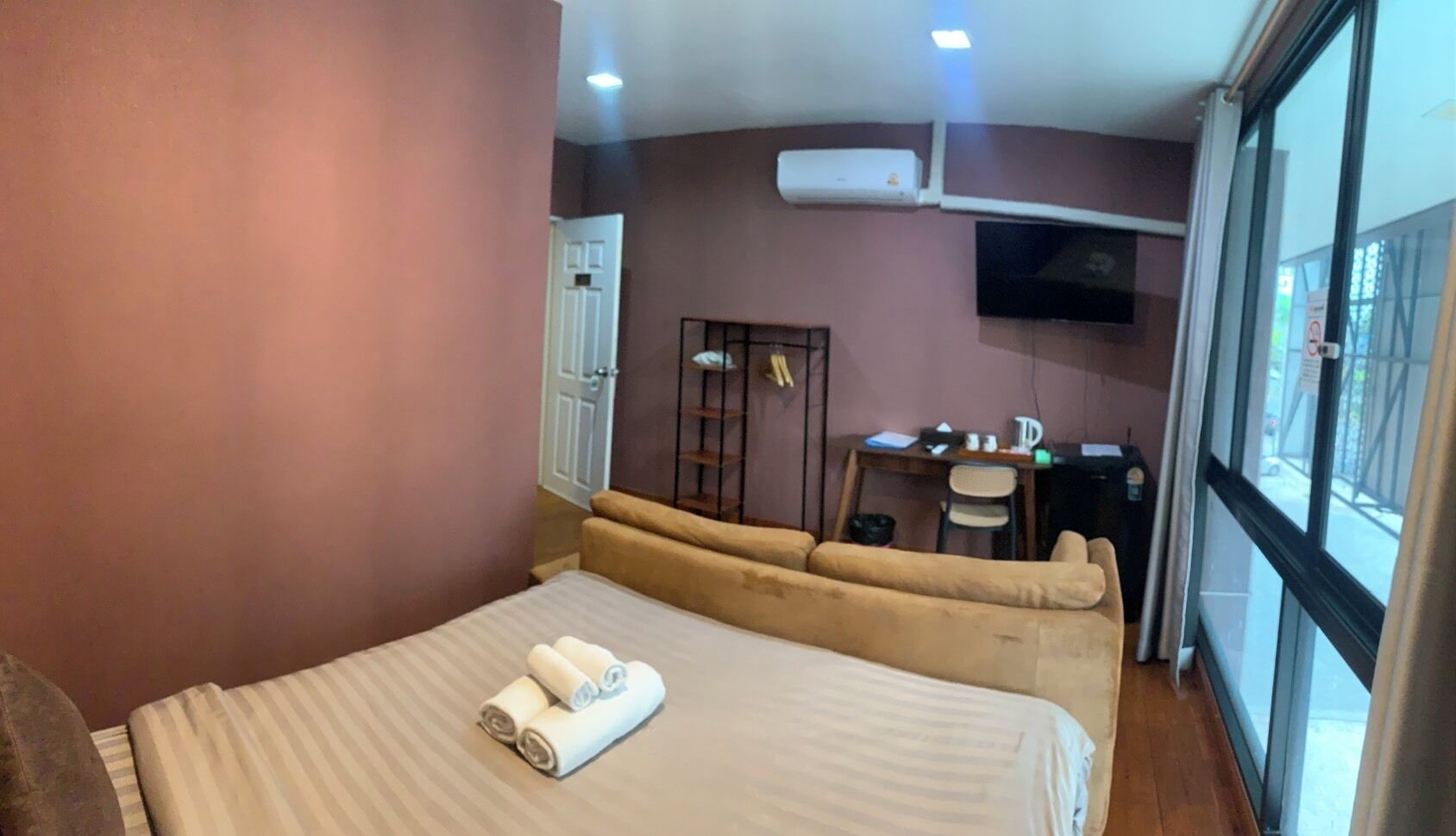 A hotel room with a bed, a sofa, a desk, and a TV.