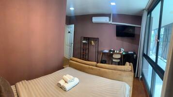 A hotel room with a bed, a sofa, a desk, and a TV.