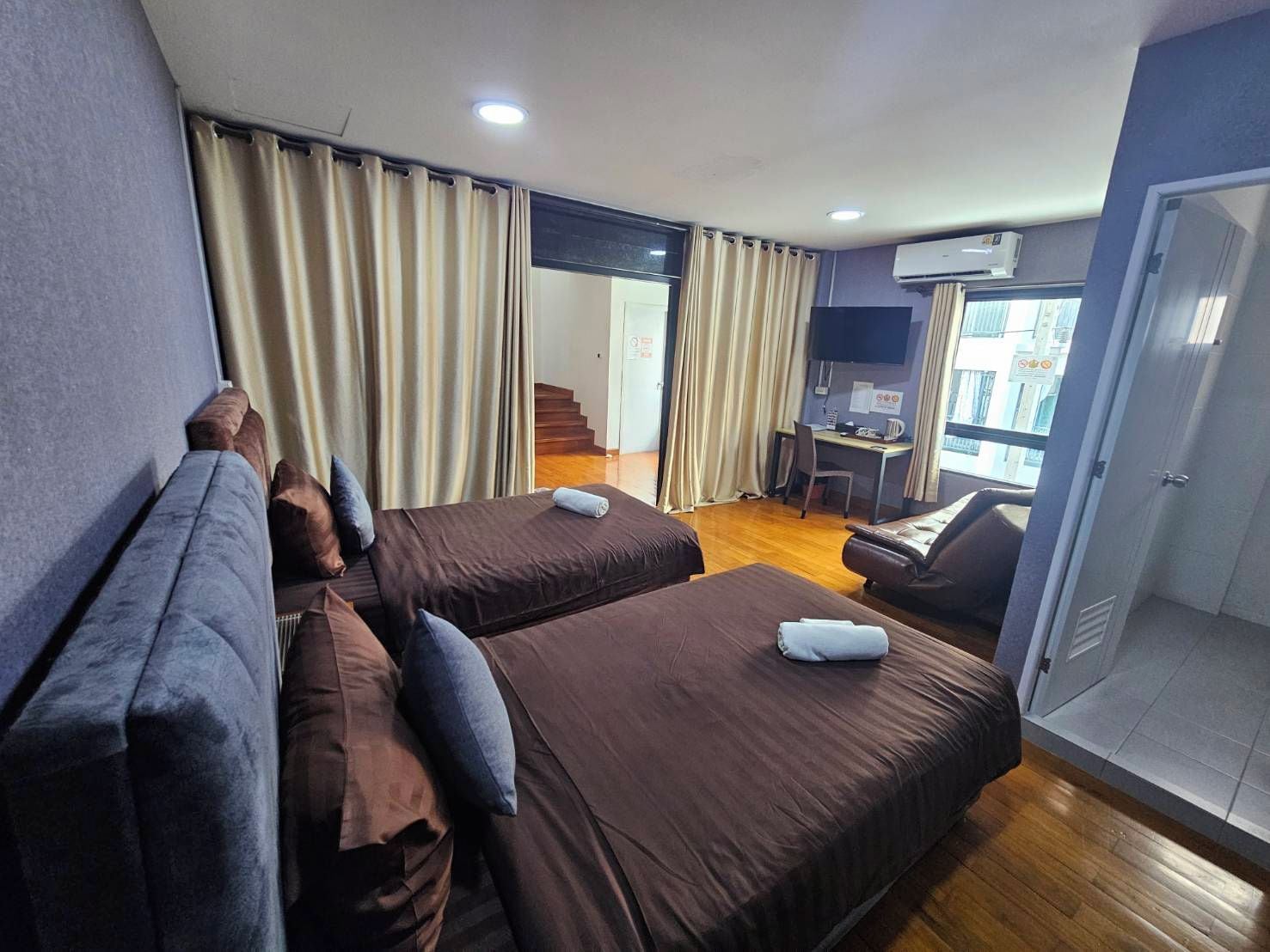Ein Hotelzimmer mit zwei Betten, einem Schreibtisch, einem Stuhl und einem Fenster.