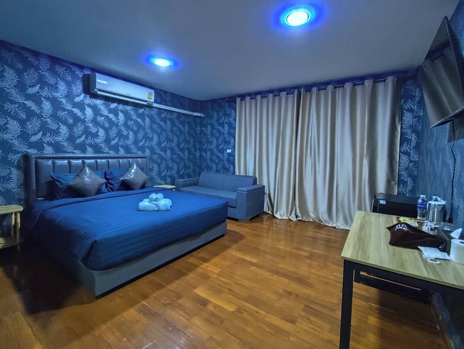 A hotel room with a bed, a sofa, a table, and a curtain.