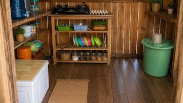 Una cocina con estantes de madera, una estufa y diversos utensilios de cocina.