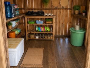 A kitchen with wooden shelves, a stove, and various kitchen items.