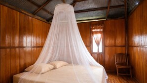 Una stanza con un letto a baldacchino, pareti in legno, una sedia e una finestra con tende.