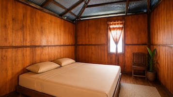 Una habitación de madera con una cama, una ventana con cortinas, una silla y una planta en maceta.