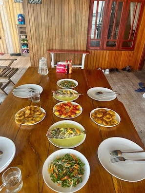 A wooden dining table with various dishes and utensils.