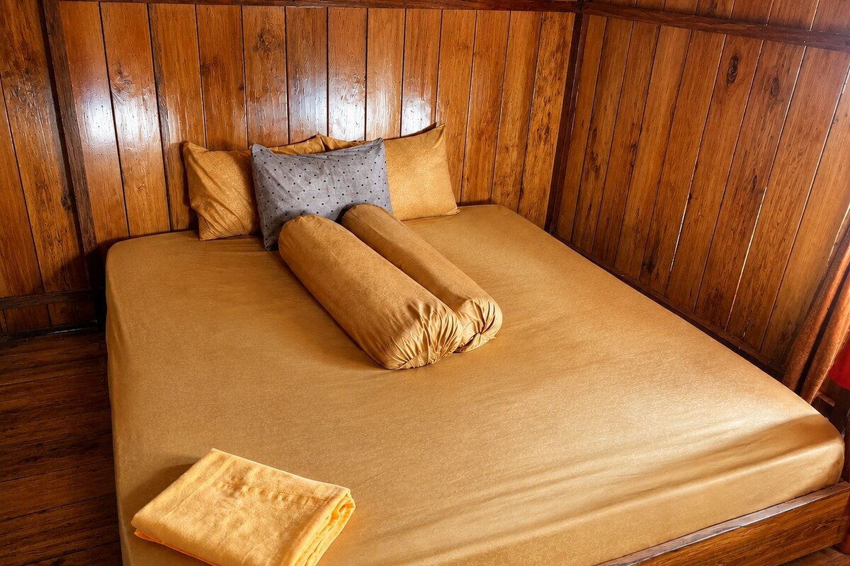 A bed with a wooden headboard, a matching blanket, and two pillows.