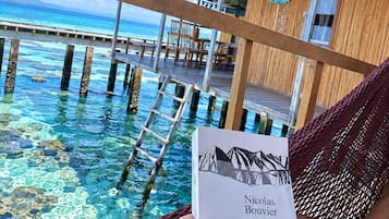 A wooden structure with a thatched roof overlooking a clear blue sea.