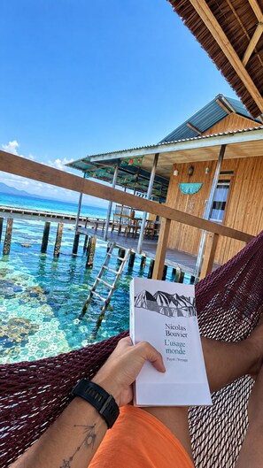 A wooden structure with a thatched roof overlooking a clear blue sea.