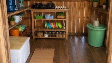 A kitchen with wooden shelves, a stove, and various kitchen items.