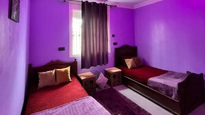 A bedroom with two beds, purple walls, and a ceiling light fixture.
