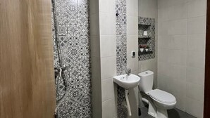 A bathroom with patterned tiles, a sink, toilet, and a shower.