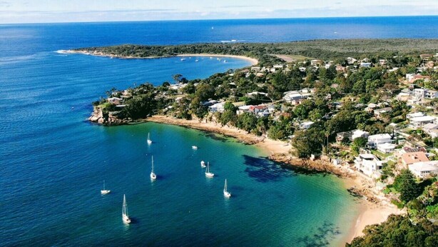 An aerial view of a coastal town with clear blue waters, several sailboats, and a mix of residential and natural landscapes. - Bayside Luxury Retreat with Pool Near to Cronulla (Port Hacking)