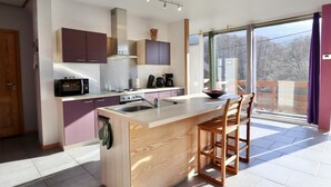 A modern kitchen with a central island, built-in appliances, and a large window offering a view.