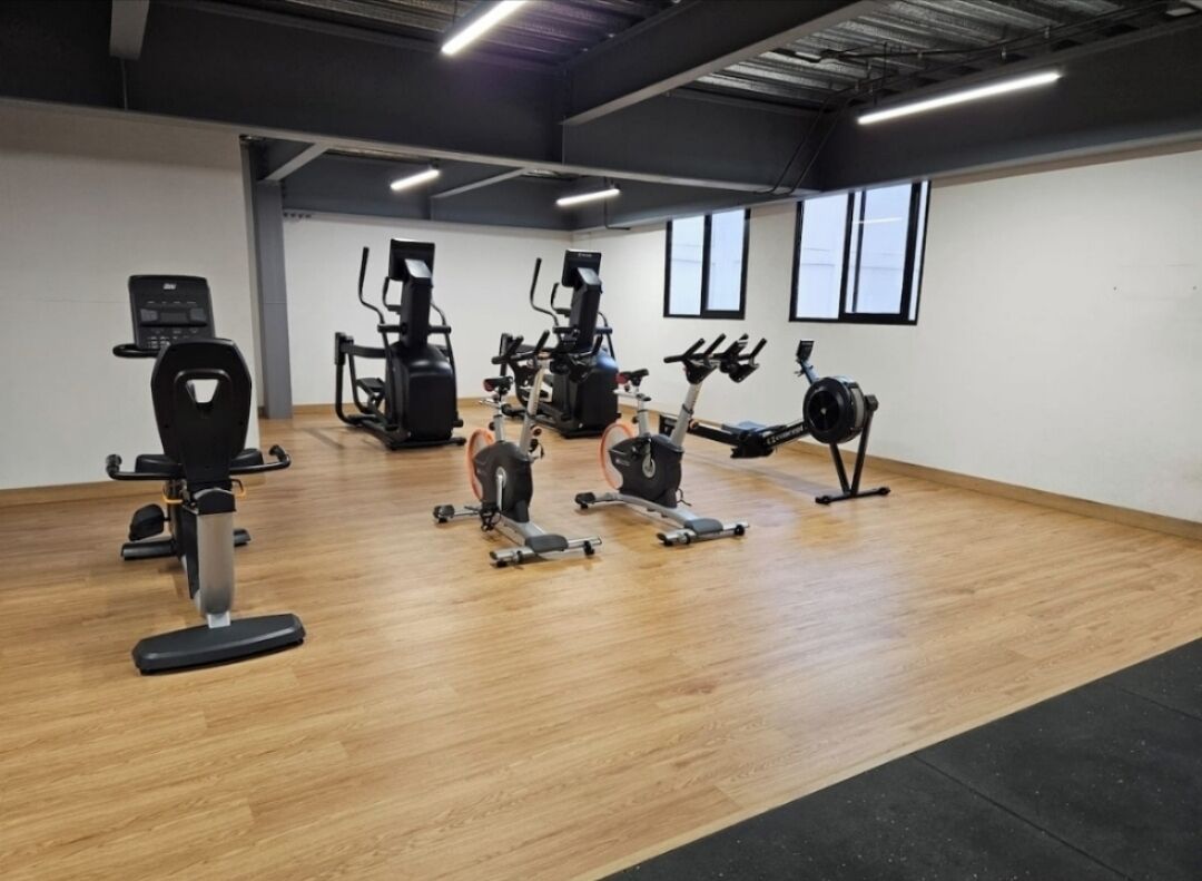 Un gimnasio con máquinas de cardio, máquinas de pesas y un muro de espejos.