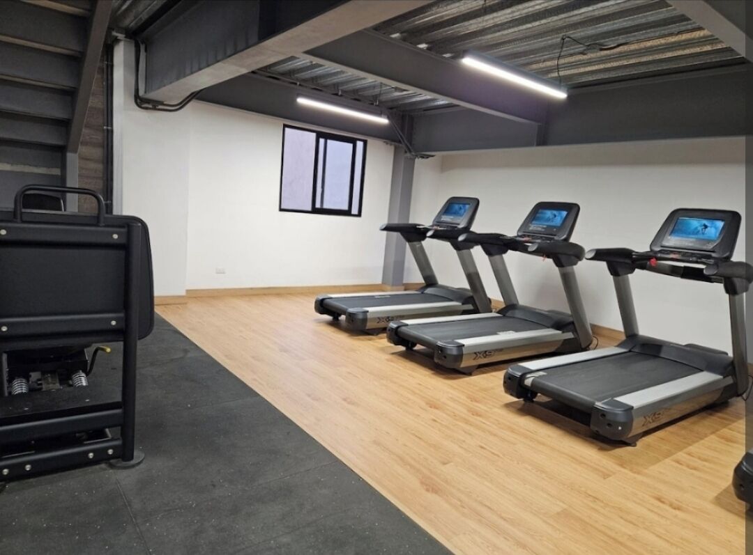 A gym with treadmills, a black exercise machine, and a window.