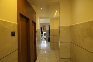 Un pasillo con una puerta identificada con la etiqueta 'E4' que da a una habitación, suelo de baldosas e iluminación empotrada en el techo.